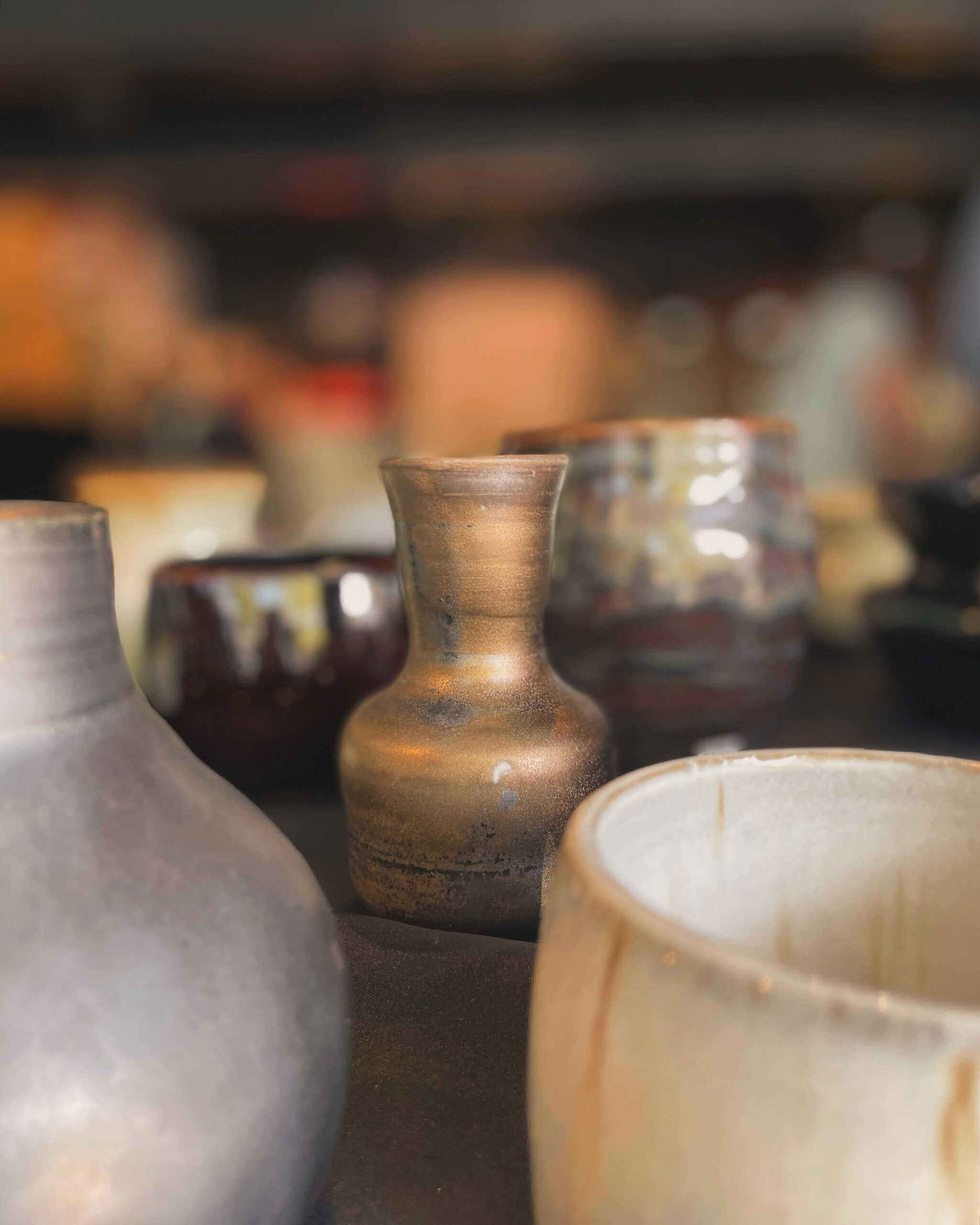 Collection de vases en céramique artisanale, avec un petit vase doré en premier plan.