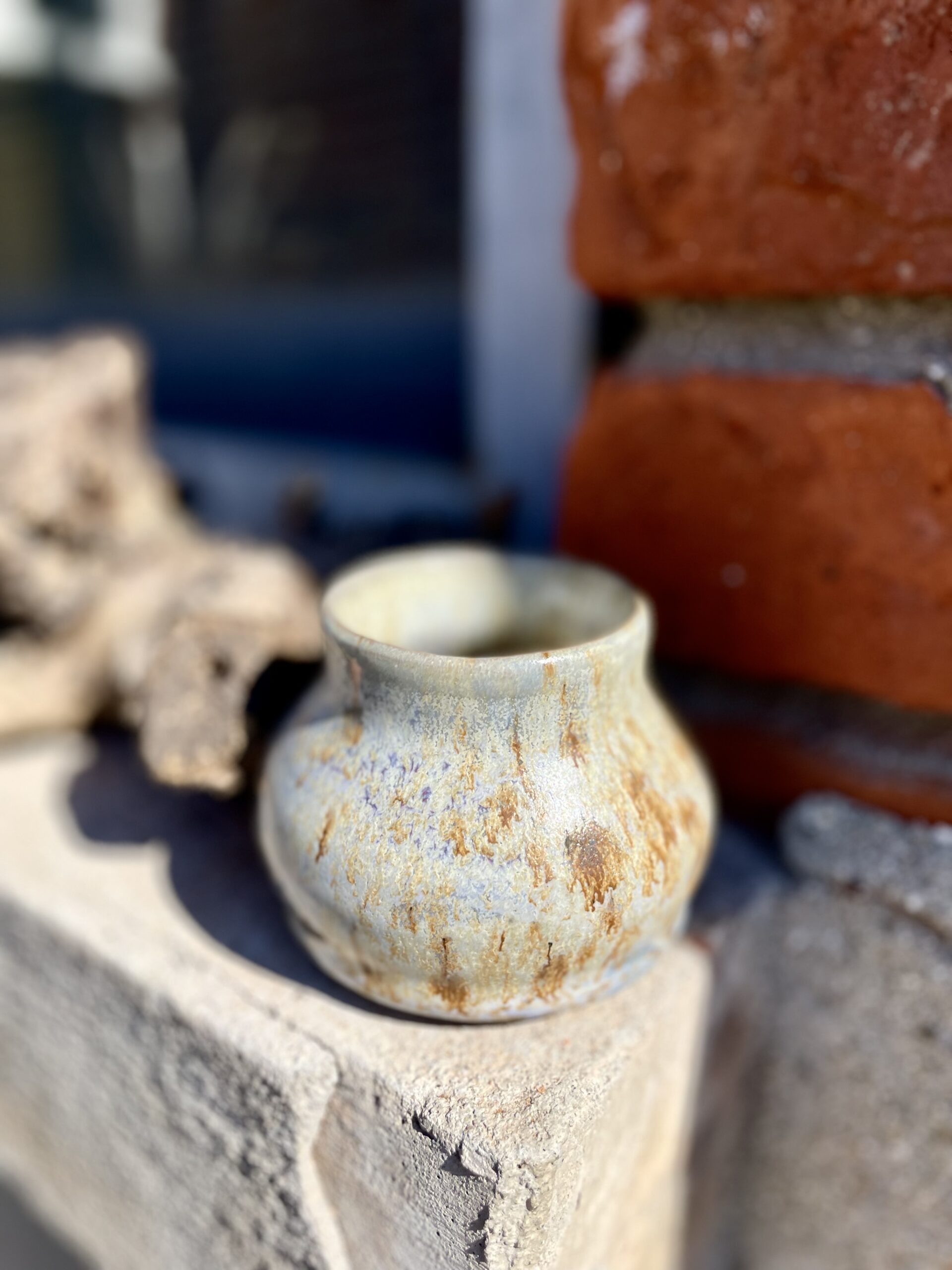 Petit pot artisanal doré avec reflets violets.