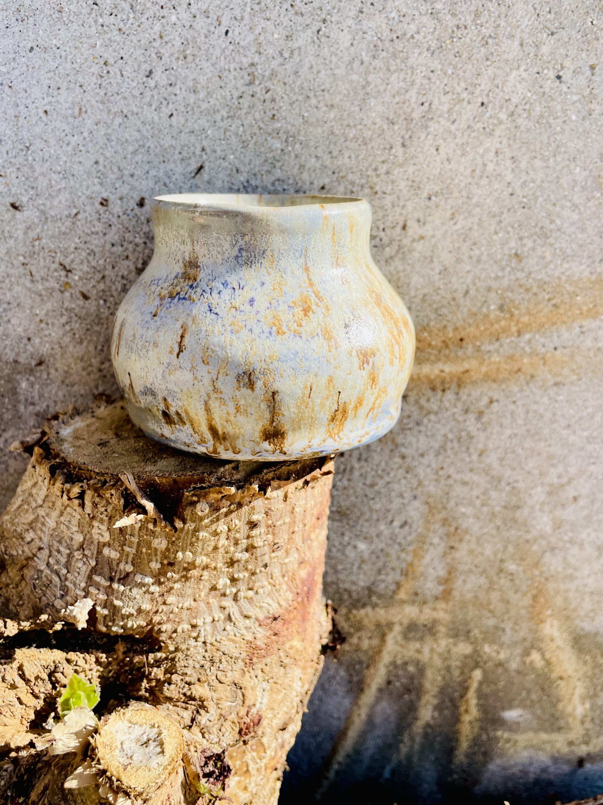 Petit pot artisanal doré avec reflets violets.